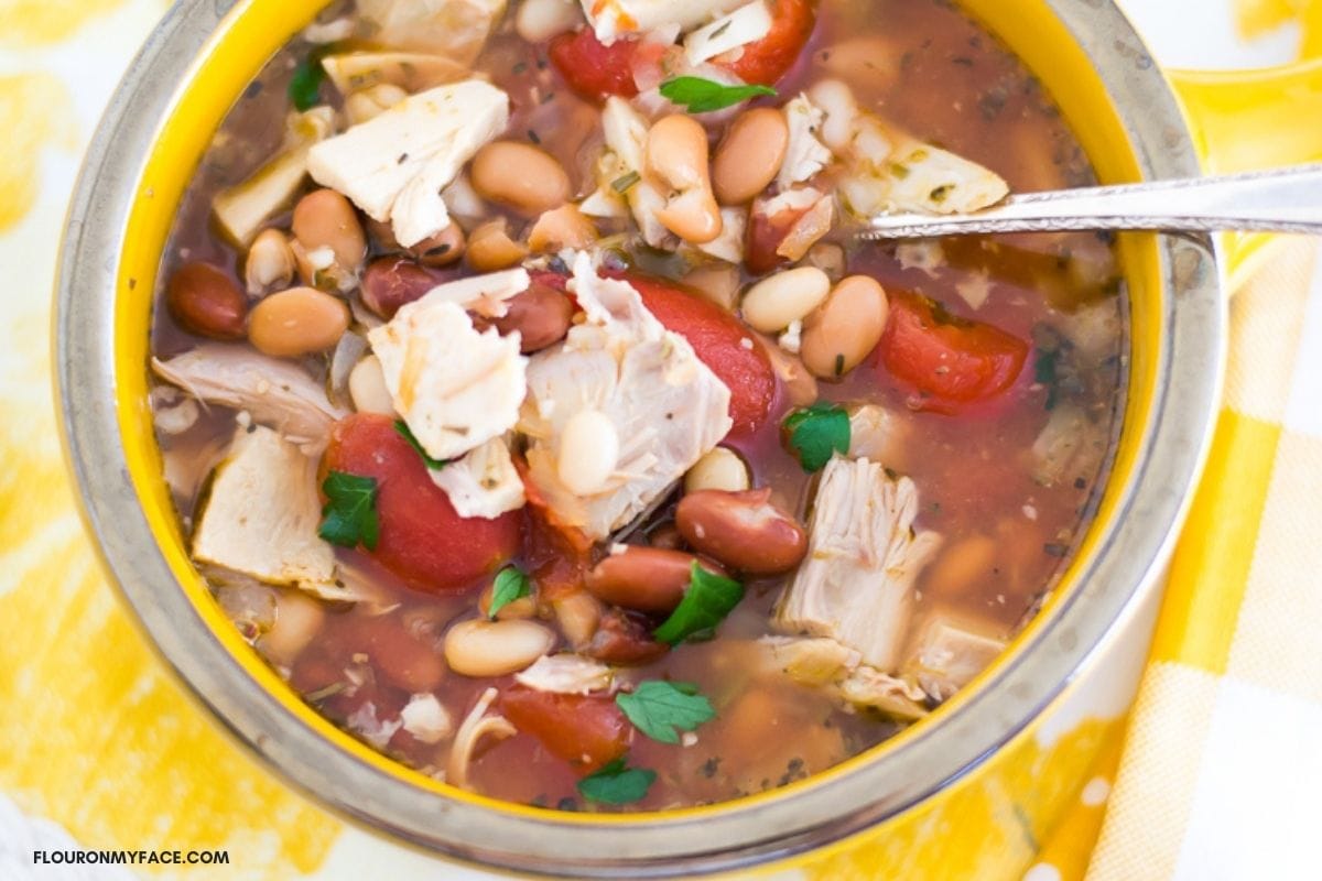 Overhead photo of Turkey and three bean soup in a yellow soup bowl.