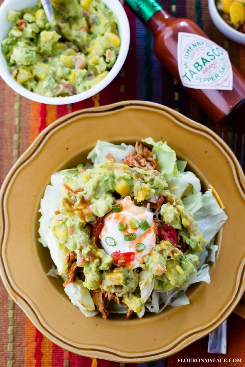 Chicken Taco Salad topped with chunky mango guacamole with sour cream and Tabasco Sauce