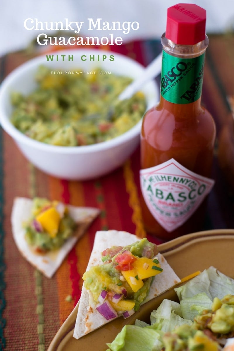 Chunky Mango Guacamole on chips with sour cream, green onions and Tabasco sauce