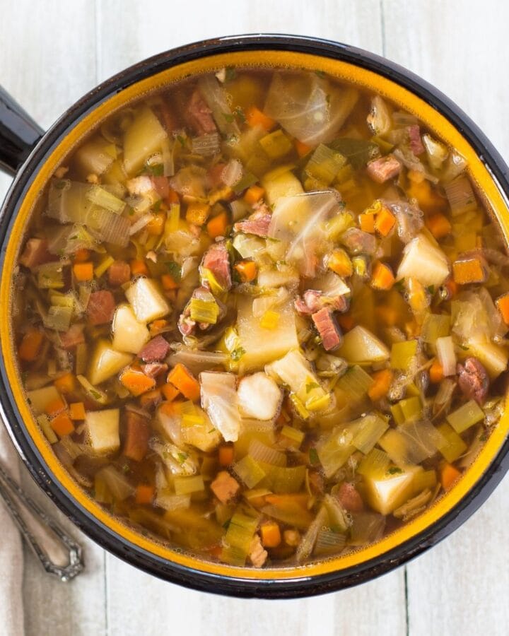A large brown soup serving bowl filled with Ham Cabbage Potatoes Soup