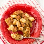 Crock Pot Eggnog Bread Pudding recipe served on a festive red deesert plate with a Christmas napkin