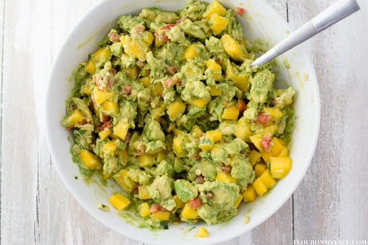 Chunky Mango Guacamole recipe in a white serving bowl with a spoon