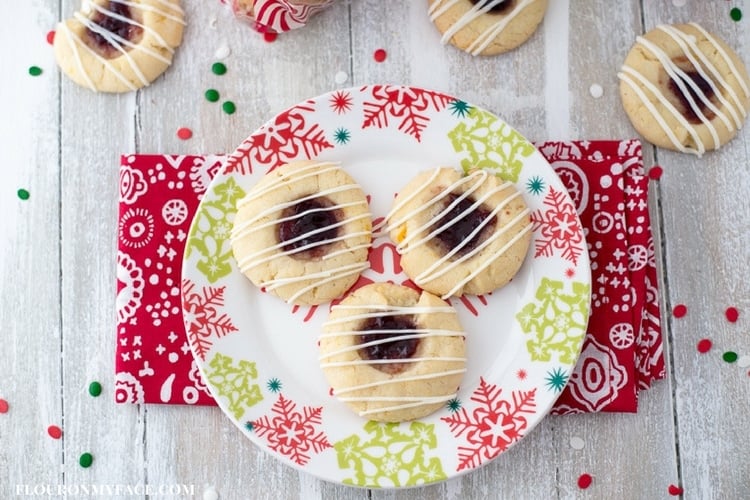 Raspberry Jam Thumbprint Cookies on a Christmas plate with a red and white Christmas cloth napkin