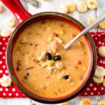 Slow Cooker Chicken Santa Fe Soup recipe served in a red soup bowl on a red cloth napkin with vintage silverware spoons