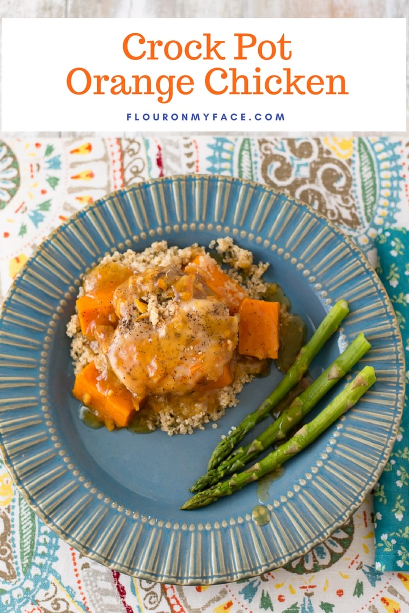 Crock Pot Orange Chicken with Sweet Potatoes served on a blue plate with fresh asparagus
