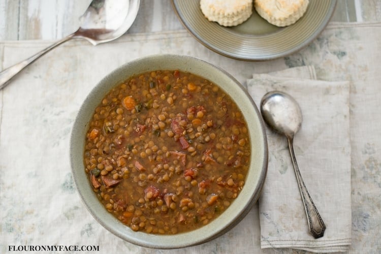 Homemade Lentil and Ham Soup in a bowl with vintage silverware and a cloth napkin.