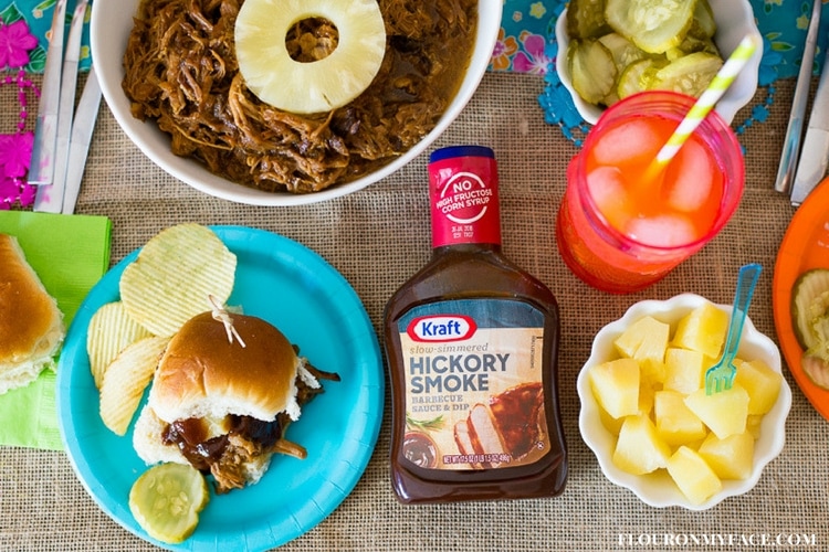 Luau game night Crock Pot Pineapple Pulled Pork Sliders recipe served with potato chips, pineapple chunks and Kraft BBQ sauce. 