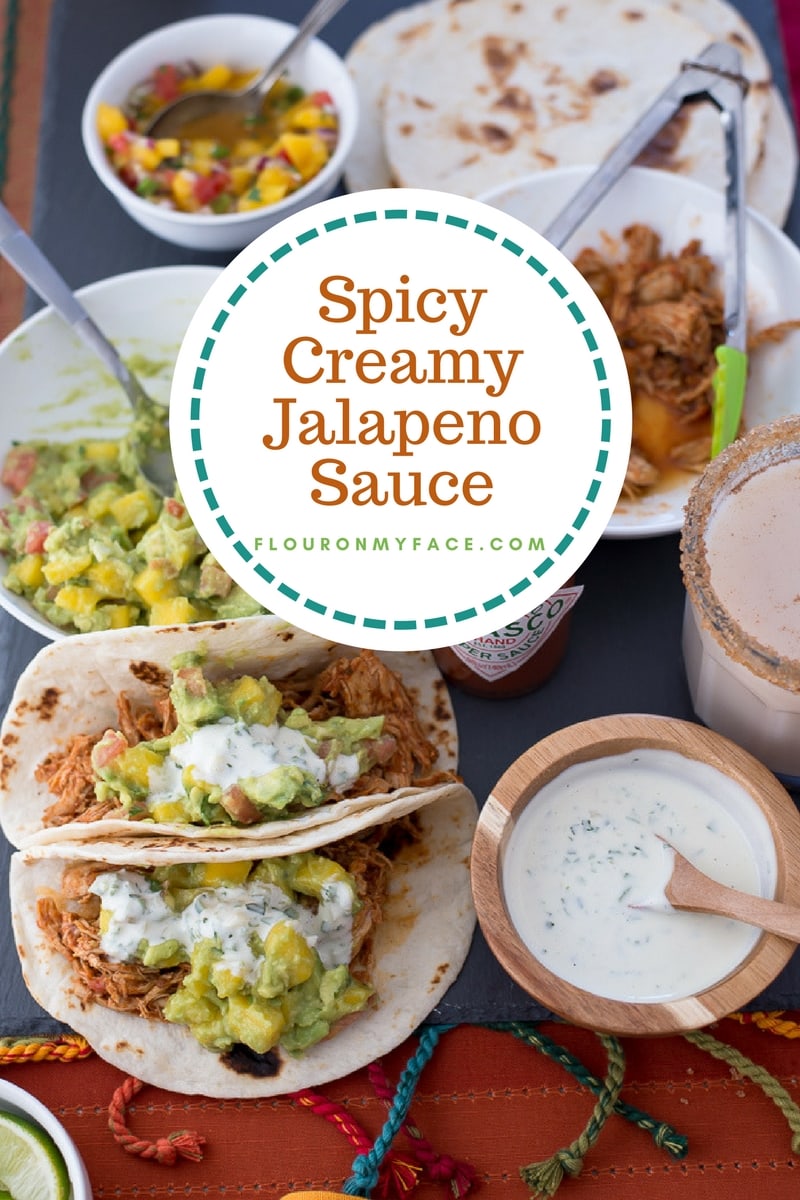 Creamy Jalapeno Sauce in a round wooden bowl served with chicken tacos, mango guacamole and homemade Horchata