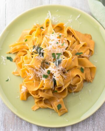 Vegetarian Pappardelle with butternut squash sauce served on a green dinner plate.