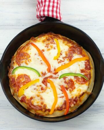 Homemade deep dish pizza baked in an iron skillet.