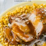 Crock Pot Pork Loin recipe made with apricot glaze served on a yellow Fiestaware platter with rice and corn.