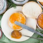 Homemade Peach Rosemary Jam Recipe spread on a biscuit with a vintage butter knife.