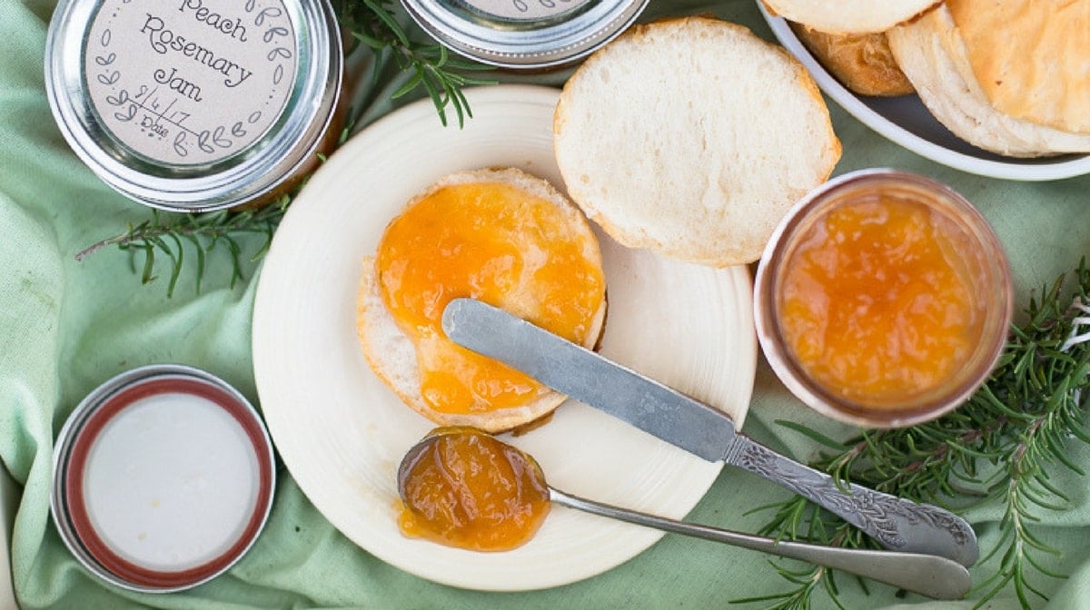 Homemade Peach Rosemary Jam Recipe spread on a biscuit with a vintage butter knife.