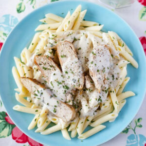 Basil Alfredo Sauce recipe served with chicken and pasta on a blue plate