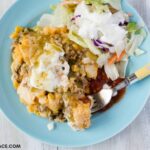 A serving of Crock Pot Mexican Cornbread Casserole with a side salad and toppings.