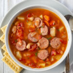 a soup bowl filled with kielbasa soup that was made in the crock pot