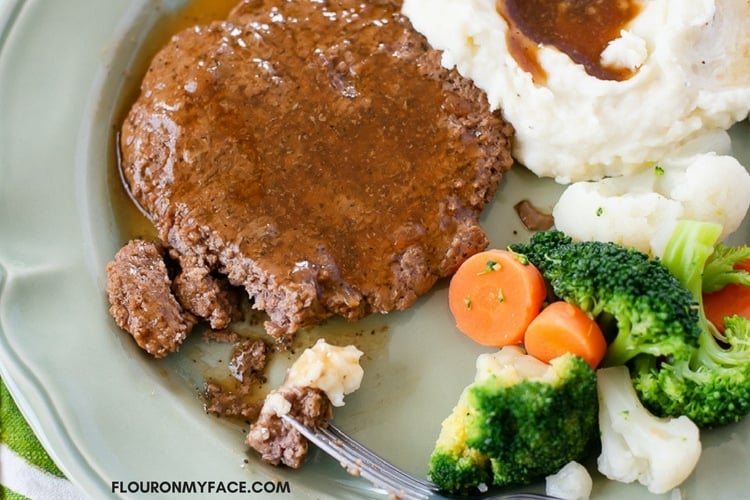 Crock Pot Cube Steak  smothered in gravy on a dinner plate with mashed potatoes and vegetables