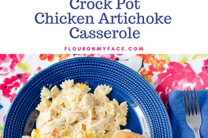 Cheesy Crock Pot Chicken Artichoke Casserole on a blue plate served with a dinner roll