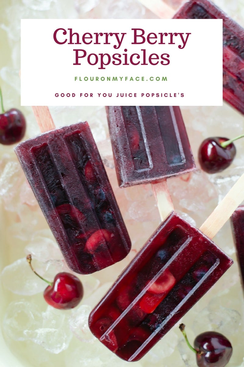 Homemade real fruit juice cherry berry popsicles recipe with sliced cherries and fresh blueberries served in a vintage enamel baking pan on ice cubes.