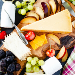 Rustic Wooden Cheese Board serving fresh summer fruit and cheese platter appetizers.