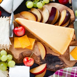 Cheese, fruit, nuts and crackers for a Cheese platter on a cutting board.