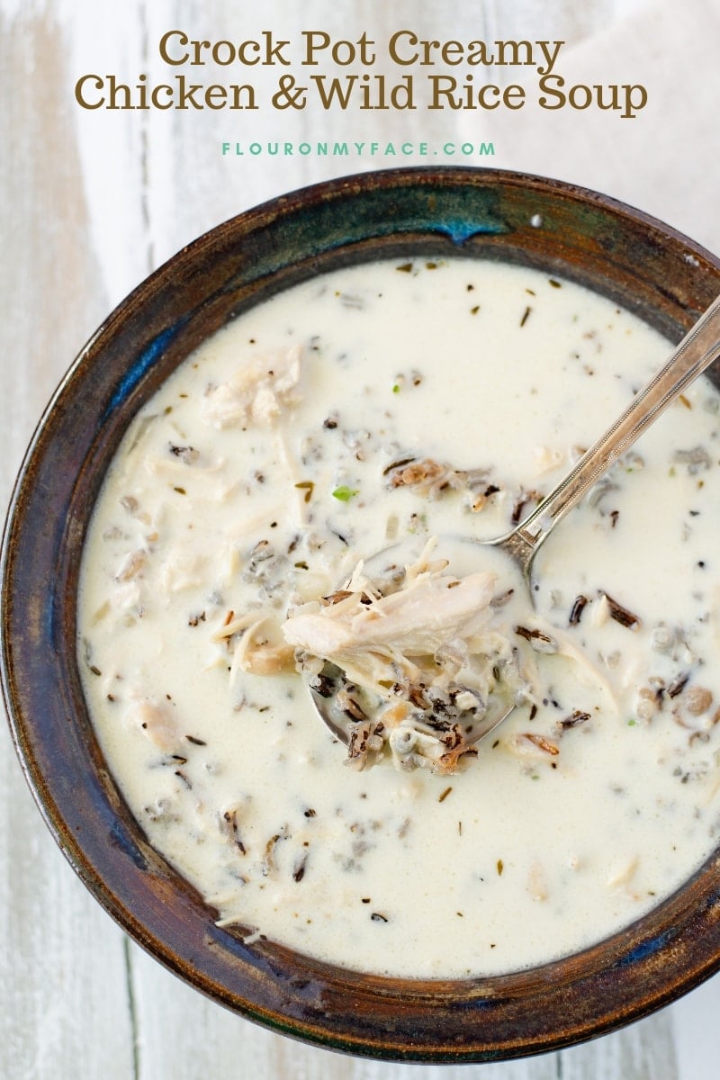 A serving of Crock Pot Chicken Wild Rice Soup in a brown ceramic bowl