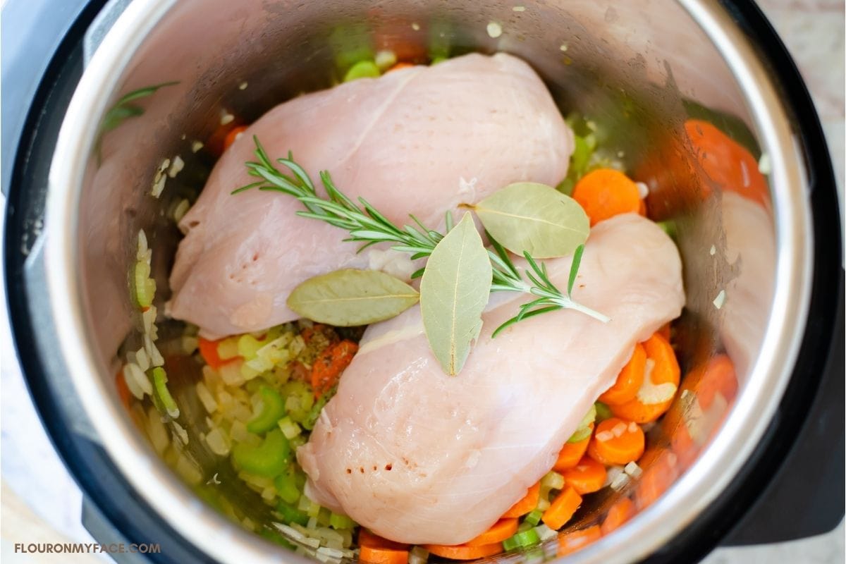 Overhead photo chicken, herbs, and vegetables before pressure cooking.