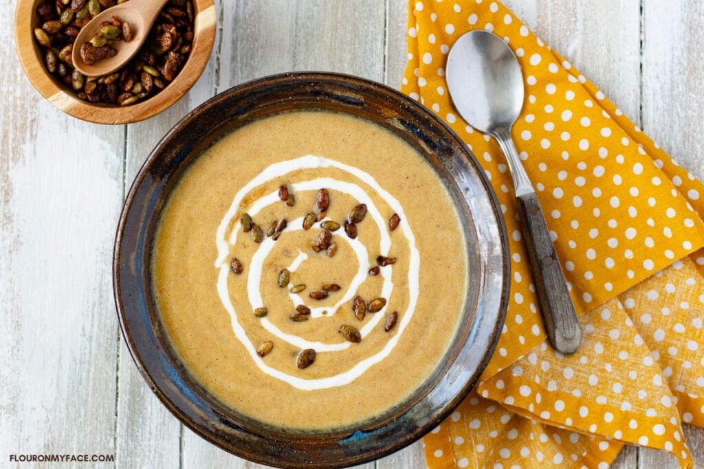 creamy pumpkin soup topped with pumpkin seeds and a swirl of sour cream