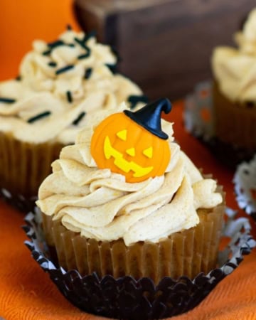Pumpkin Cupcakes topped with Pumpkin Spice Buttercream Frosting and decorated for Halloween with candy pumpkins and sprinkles