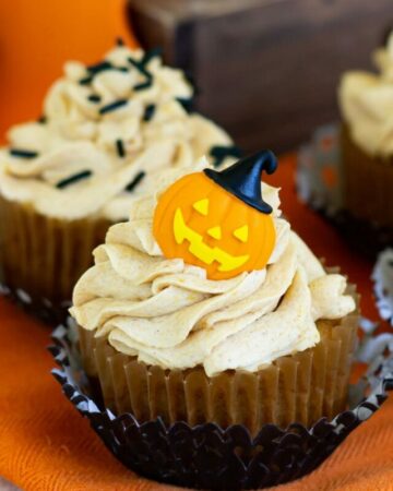 Pumpkin Cupcakes topped with Pumpkin Spice Buttercream Frosting and decorated for Halloween with candy pumpkins and sprinkles