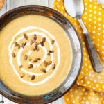 Crock Pot Pumpkin Soup made with homemade pumpkin puree topped with cinnamon maple toasted pumpkin seeds.