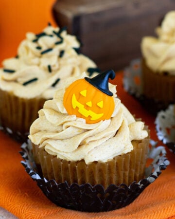 Pumpkin Cupcakes topped with Pumpkin Spice Buttercream Frosting and decorated for Halloween with candy pumpkins and sprinkles