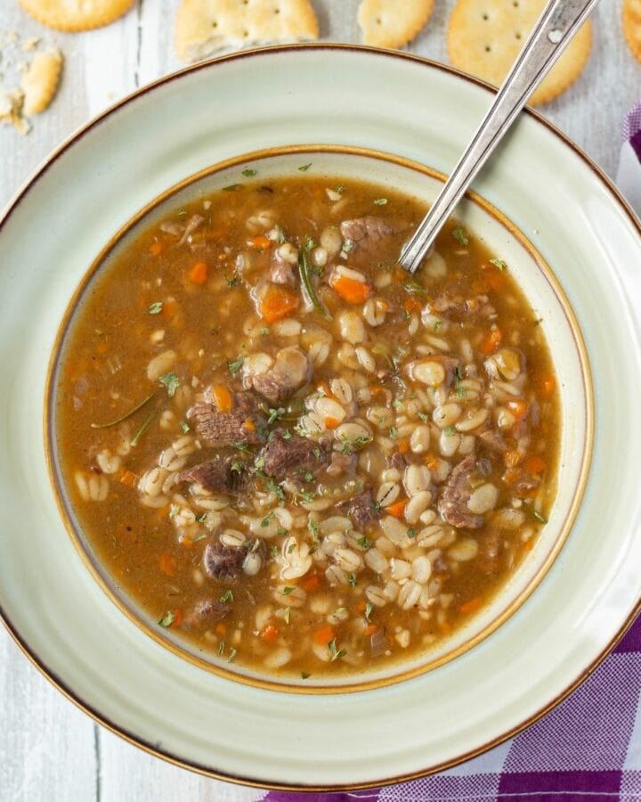 A bowl filled with beef barley soup with a rich and thick broth.
