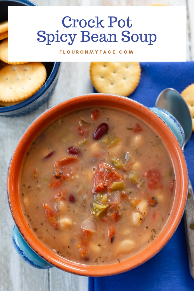 A heaping bowl full of Crock Pot Spicy Bean Soup recipe with a bowl of crackers.