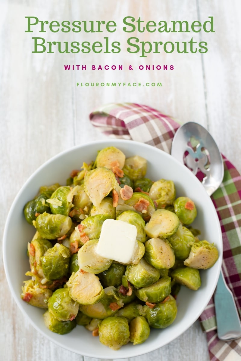 A large white serving bowl of Instant Pot Brussels Sprouts with a mauve and green plaid cloth napkin.