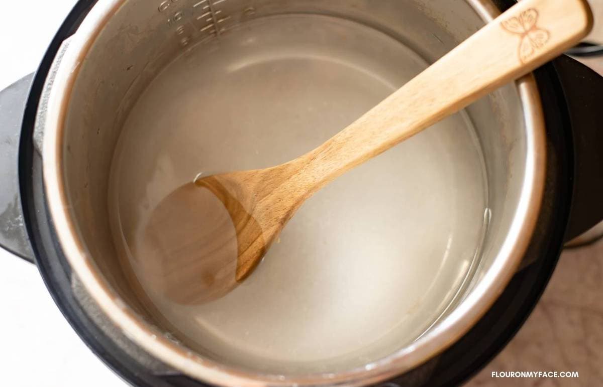 Cloudy salted water in the pot with a wooden spoon.