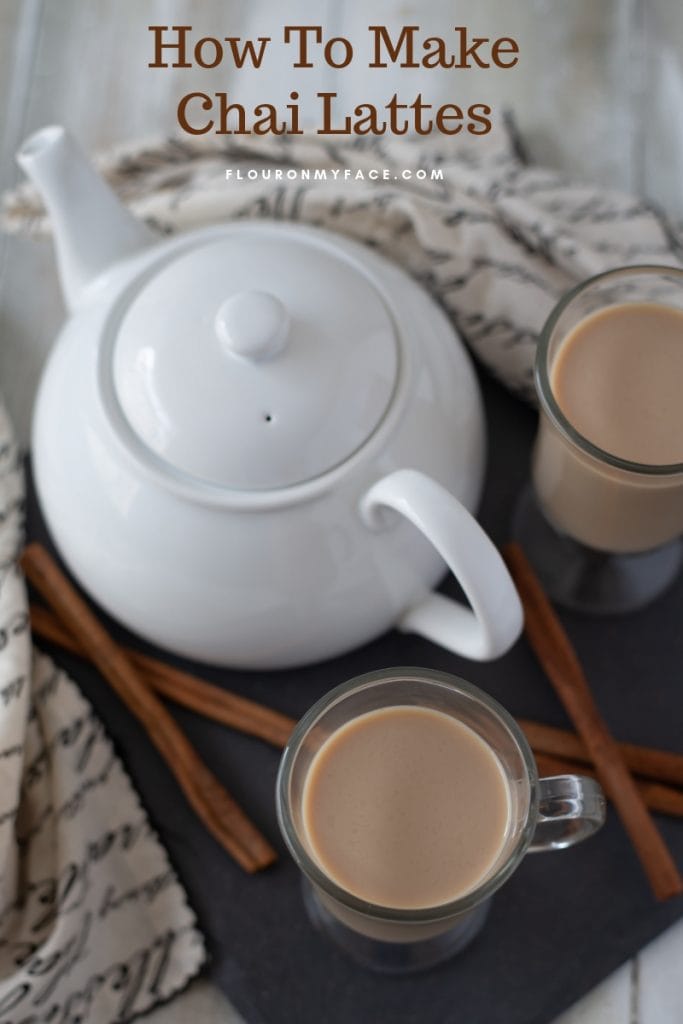 Homemade Chai Lattes, with a white tea pot and cinnamon sticks
