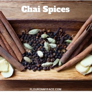 A wooden bowl with cinnamon sticks, peppercorns, cardamon pods, whole cloves and fresh ginger slices. All the spices you need to make a chai tea latte at home