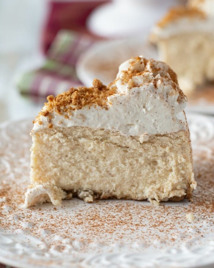 Eggnog cheesecake topped with whipped cream and dusted with cinnamon on a plate.