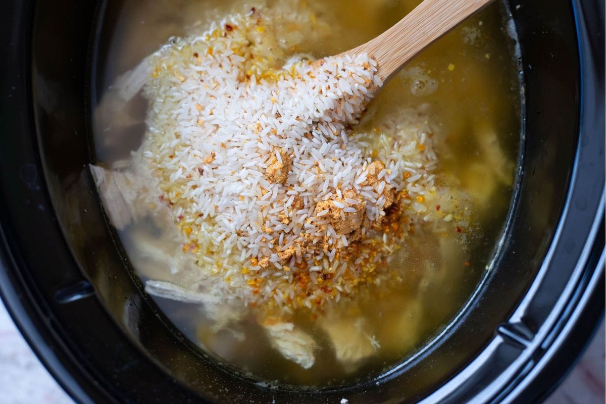 Adding yellow rice to the crock pot.