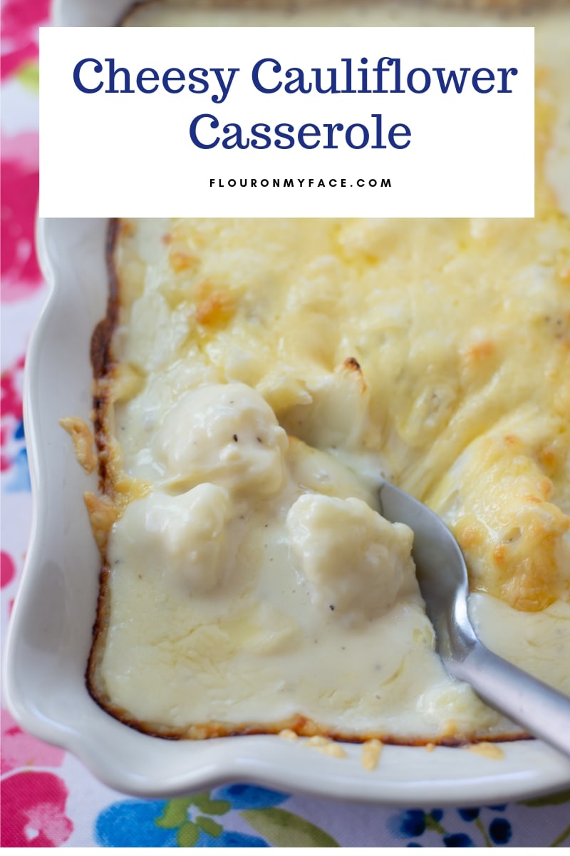 A baking dish of cheesy Gouda Cauliflower Casserole with a spoon scooping a serving.