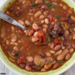 A green vintage bowl with a serving of piping hot Instant Pot Cajun 15 Bean Soup recipe.
