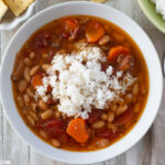 Instant Pot Ham and Bean Soup topped with white rice and served in a white bowl.