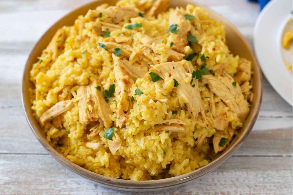 Tender chicken and yellow rice served in a clay serving bowl.
