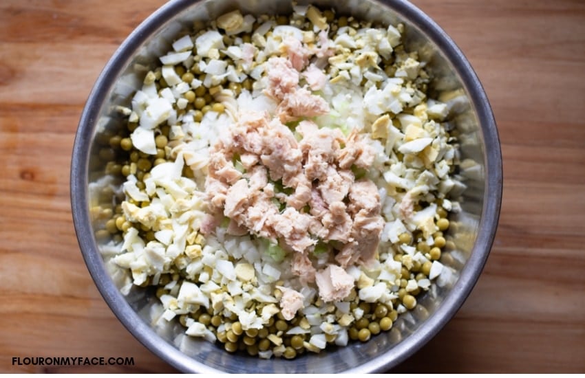 Mixing Tuna pasta salad ingredients in a stainless steel mixing bowl.