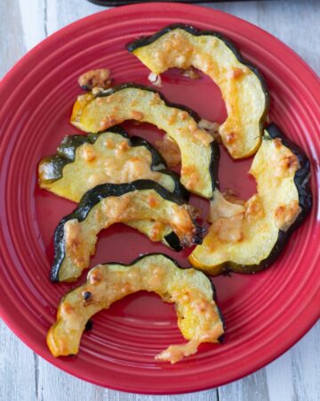 Slices of roasted acorn squash on a red plate.