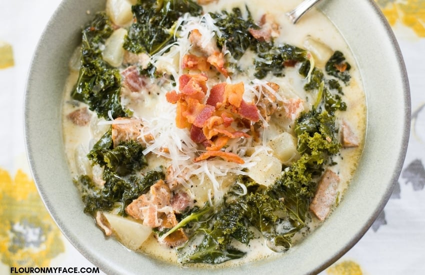 A tan bowl filled with a serving of Crock Pot Zuppa Toscana Soup recipe