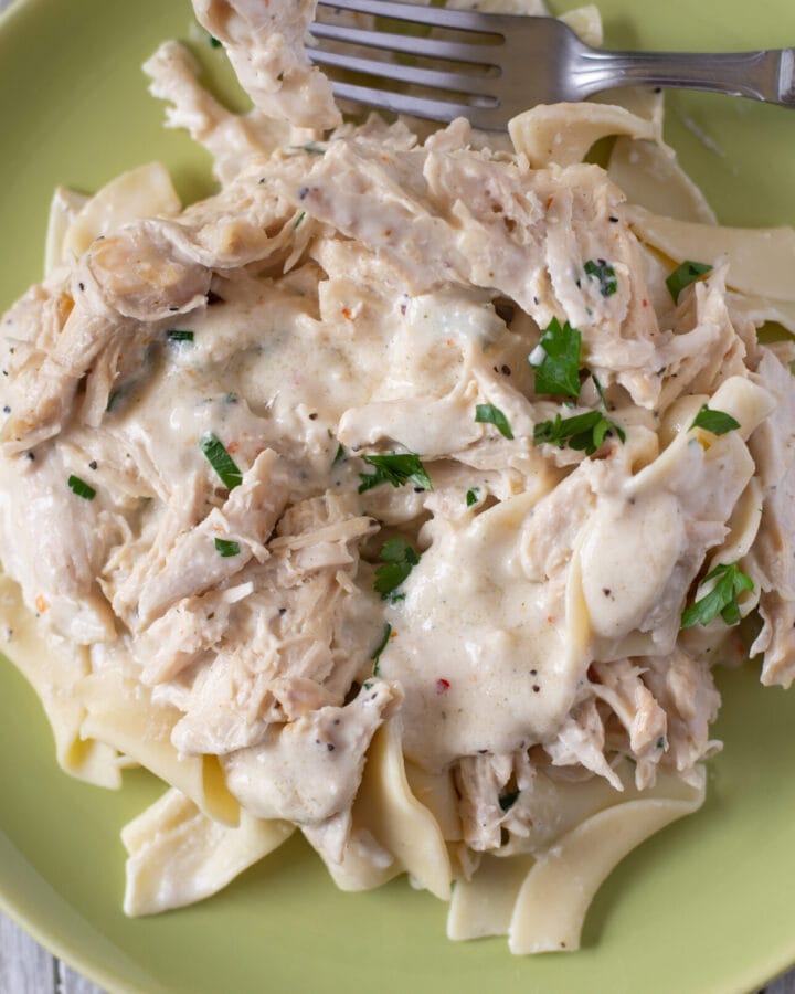 serving crock pot cream cheese chicken over cooked wide egg noodles.