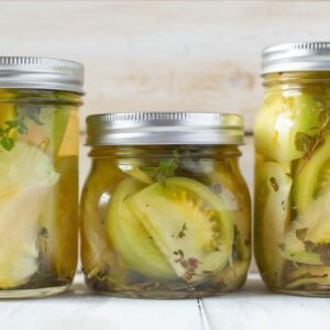 Closeup of canning jars filled with quick pickled green tomatoes.