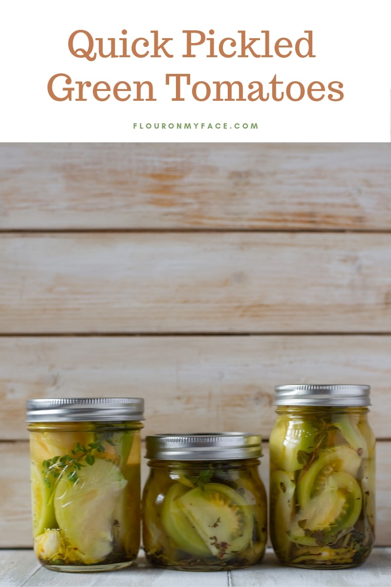 Three half pint canning jars filled with pickled green tomatoes